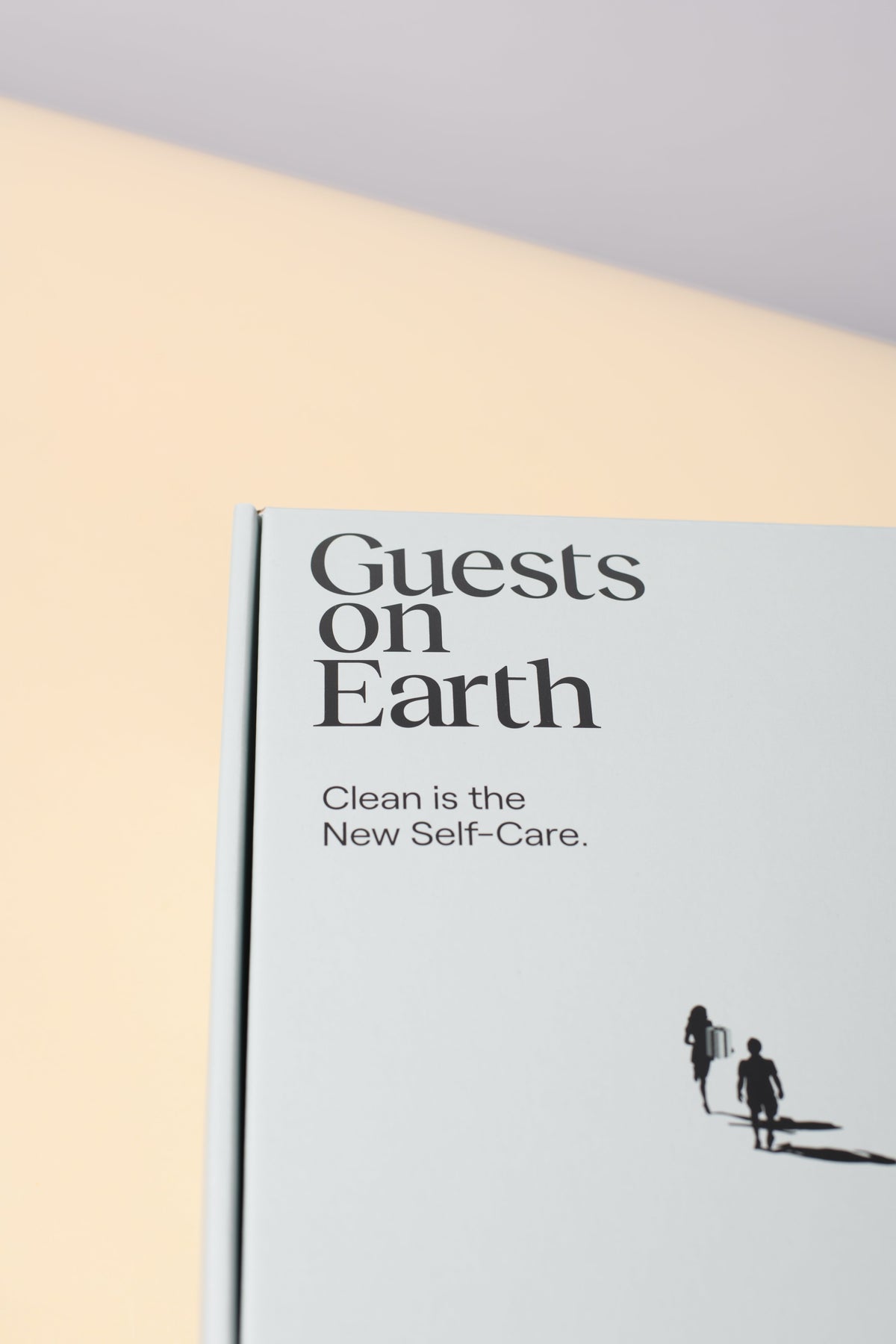 Guests on Earth gift box with minimalist white design and Clean is the New Self-Care text, close-up