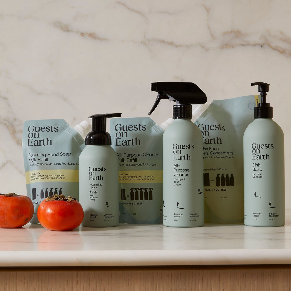 Guests on Earth non-toxic cleaning products in citrus oasis scent, bottles and refill pouches lined up on marble counter