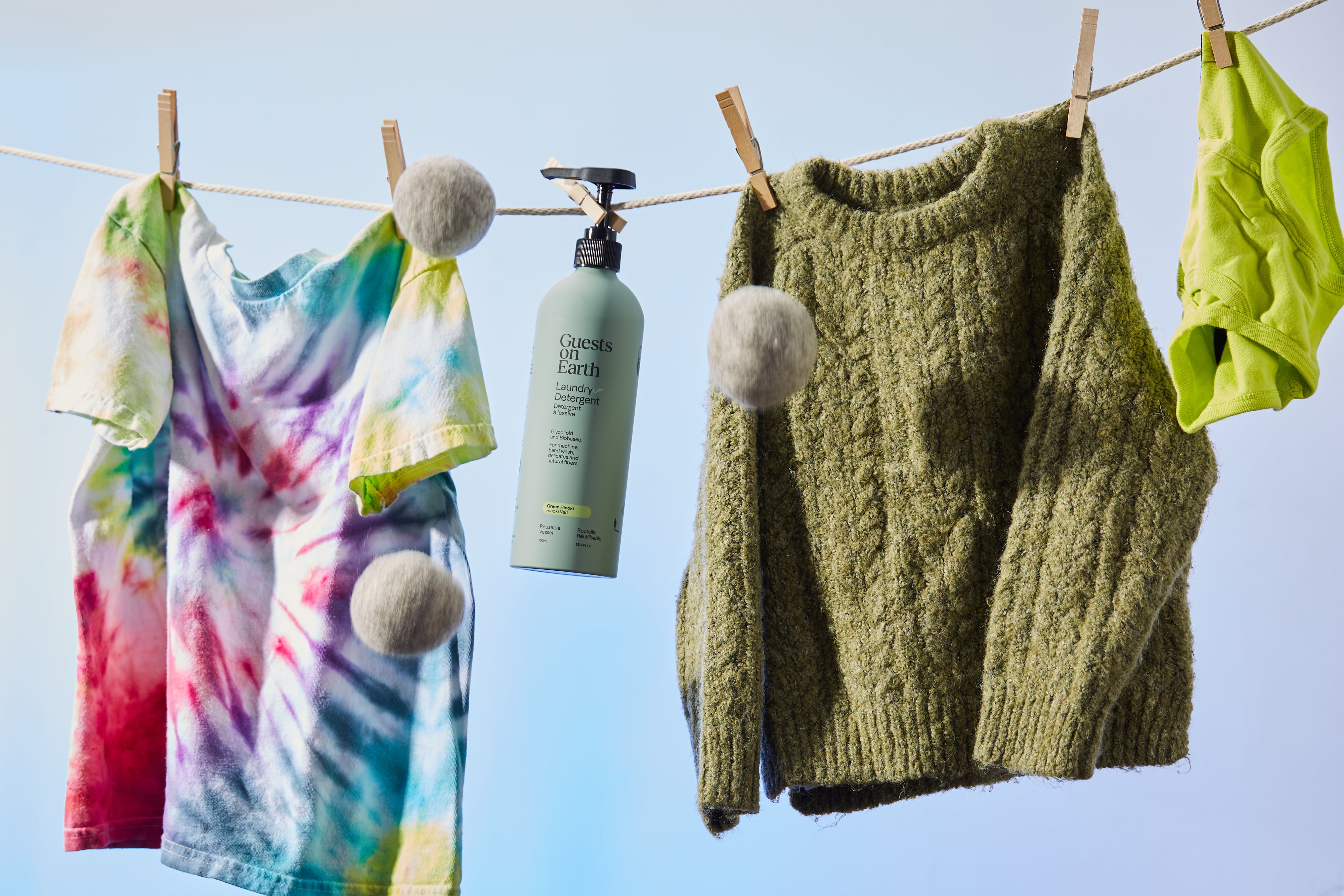 Guests on Earth Laundry Detergent, a non-toxic product, hangs on clothesline with colourful tee, sweater, and dryer balls